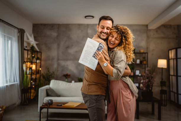 夫妻俩抱着宝宝的超声波照片互相拥抱图片下载