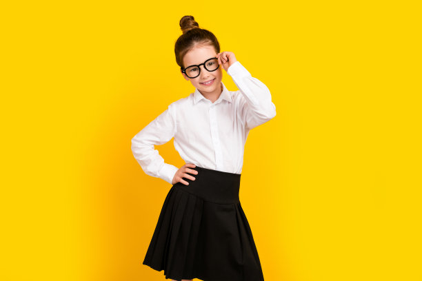 照片中可爱的女学生手臂触摸眼镜空白空间穿制服孤立的黄色背景图片下载