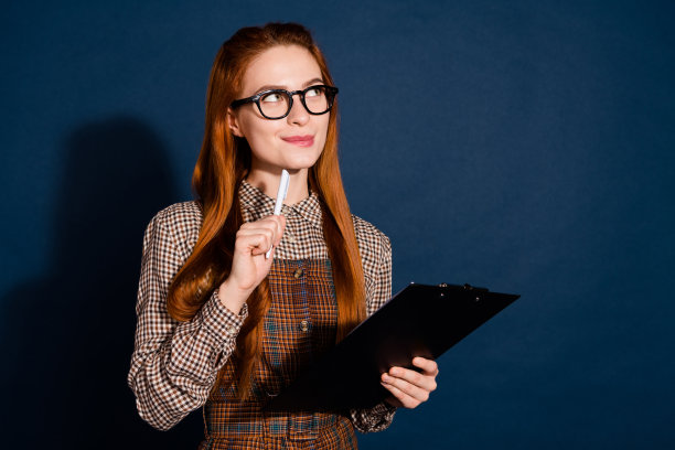 照片中甜美梦幻的女士穿着格子装，在写字板上书写，看起来空落落的深蓝色背景图片下载