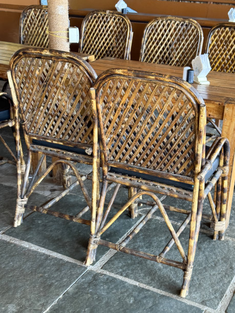 海滩餐厅的特写照片，在一排木桌下面塞着编织的竹椅，盐和胡椒罐和餐巾架，石板地砖，聚焦在前景图片下载