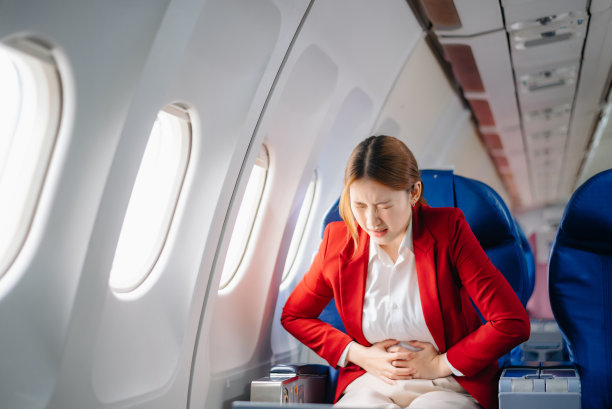 一位沮丧的女士坐在飞机上，双手抱头的照片。一位亚洲女士坐在座位上图片下载