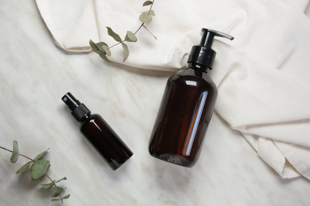 天然化妆品概念。顶视图照片的玻璃分配器瓶和桉树上孤立的大理石背景与空白的空间。图片下载