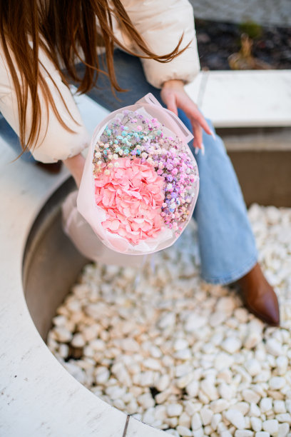 一束粉红色的牡丹和丁香和薰衣草花在女孩的手中停留在一个石头上图片下载