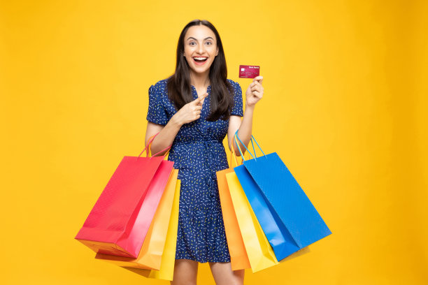 购物的照片欢快的女孩手里拿着彩色的袋子孤立在明亮生动的亮黄色背景股票照片图片下载