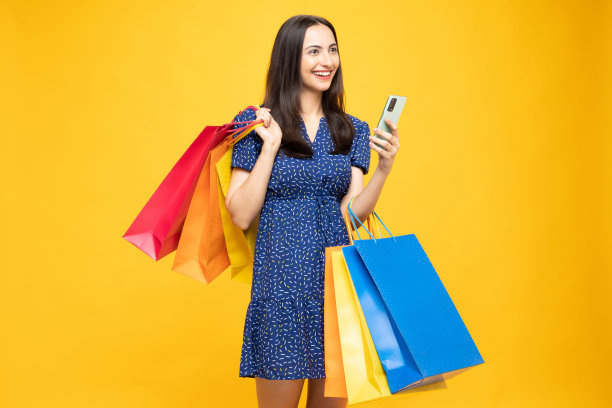 购物的照片欢快的女孩手里拿着彩色的袋子孤立在明亮生动的亮黄色背景股票照片图片下载