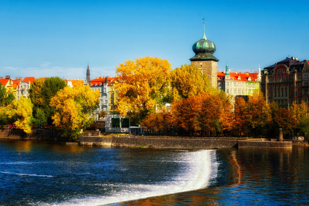 这是一张以瀑布和建筑物为背景的河流照片。古塔在河边的秋天。秋天的布拉格。景观。图片下载