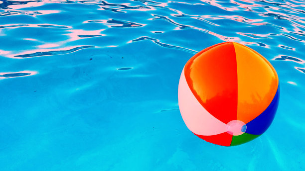 充满活力的彩色沙滩球在前景游泳池在黄金时间空间复制•股票照片图片下载