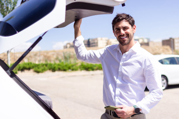 推销员微笑着拿着电话，打开汽车后备箱图片下载