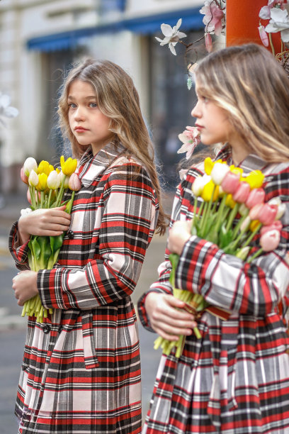 一个十几岁的女孩拿着郁金香站在街上的镜子前。春天。城市的照片。反射图片下载