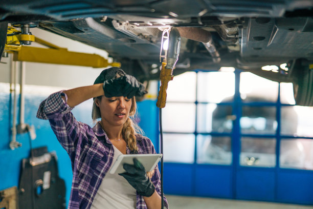 一名女机械师在一家汽车修理店工作时手持数码平板电脑的照片图片下载