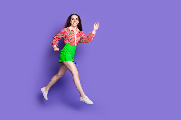 可爱的年轻女士跑步的全身照片有乐趣穿着时尚的粉红色服装孤立的紫罗兰色背景图片下载