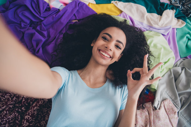 上图是漂亮的年轻女孩自拍秀的照片，象征凌乱凌乱的衣服在室内平坦图片下载