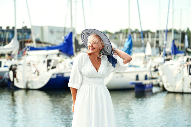 优雅美丽的金发女郎在船上摆姿势。夏天的照片。戴着时髦帽子的迷人女人。图片下载