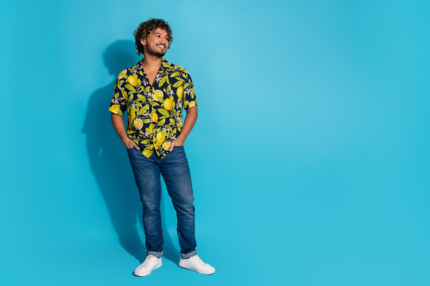 全尺寸照片积极的男人穿着印花衬衫牛仔裤手臂在口袋里看销售空空间孤立的蓝色背景图片下载