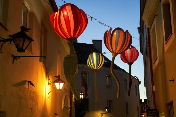 黄昏时分，巨大的人造花悬挂在老街上图片下载