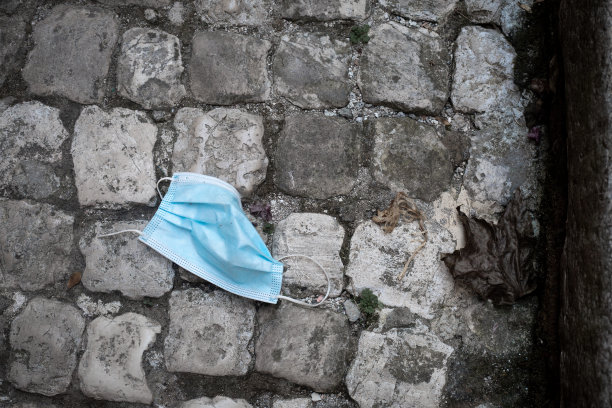 水平的画面。使用过的蓝色医用桅杆FFTP-2在灰色的鹅卵石路面上皱眉。黑白配蓝。对比照片。污染的概念。冠状病毒。生态和循环利用。图片下载