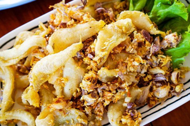 在泰国普吉岛旅游时，海鲜餐厅餐桌上的蒜椒炒河鱼特写照片。图片下载