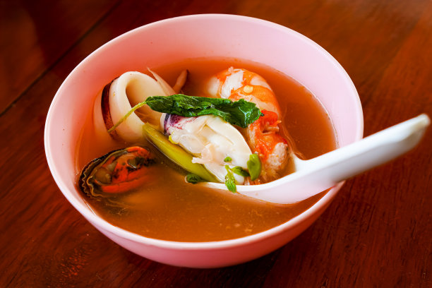 在泰国普吉岛旅游时，海鲜餐厅餐桌上的汤碗里盛着泰式辣味汤的特写照片。图片下载