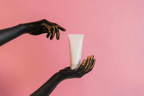 手里拿着化妆玻璃管，皮肤上涂着黑漆。展示奢华护肤产品。图片为您的设计图片下载