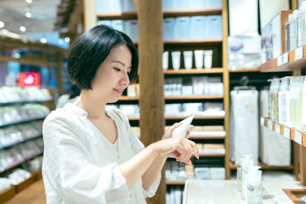 一个亚洲女孩在商店的化妆品柜台试用护手霜图片下载