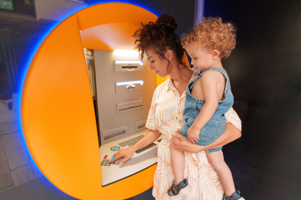 西班牙裔拉丁妇女抱着儿子使用自动取款机图片下载