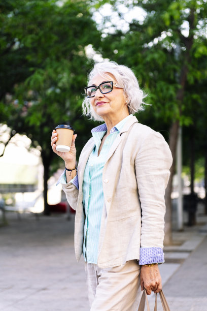 一个带着外卖咖啡走在城市里的成熟的女人图片下载