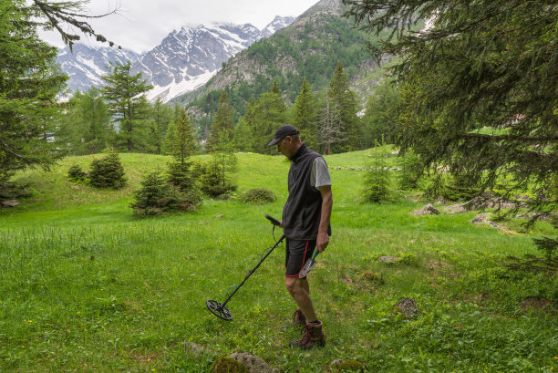 一个人在山间草地上用休闲金属探测器搜索图片下载