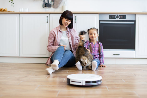 母女俩带着猫看着厨房里的机器人吸尘图片下载