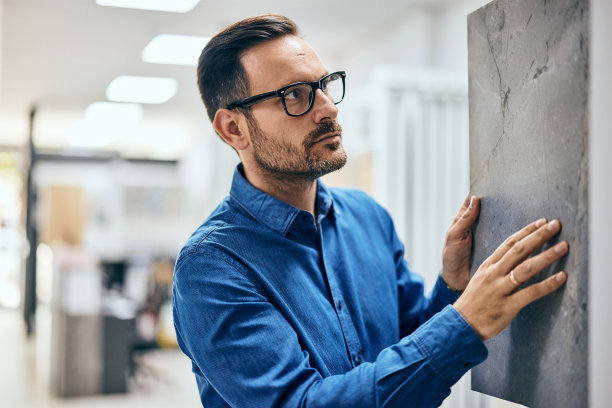一个专注的男人为他的浴室挑选瓷砖，特写照片。图片下载