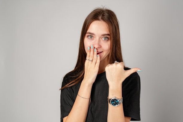 微笑的年轻女子指着灰色背景下的复制空间图片下载