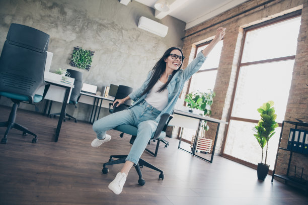 漂亮女孩的全尺寸照片骑扶手椅超级英雄飞穿时髦的牛仔服装现代职场成功企业主家庭办公室图片下载