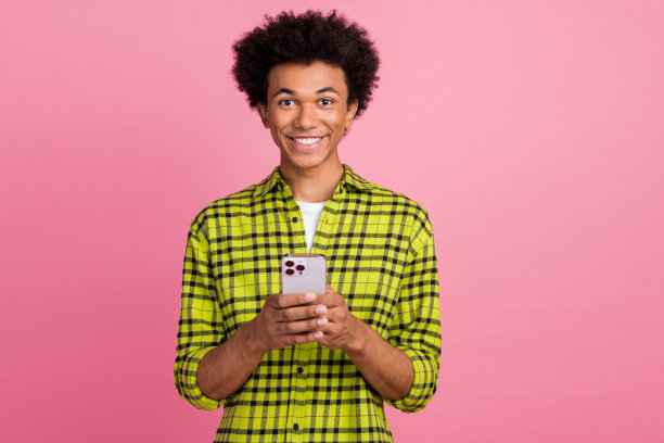 漂亮的年轻人用电话聊天的照片，穿着衬衫孤立的粉红色背景图片下载