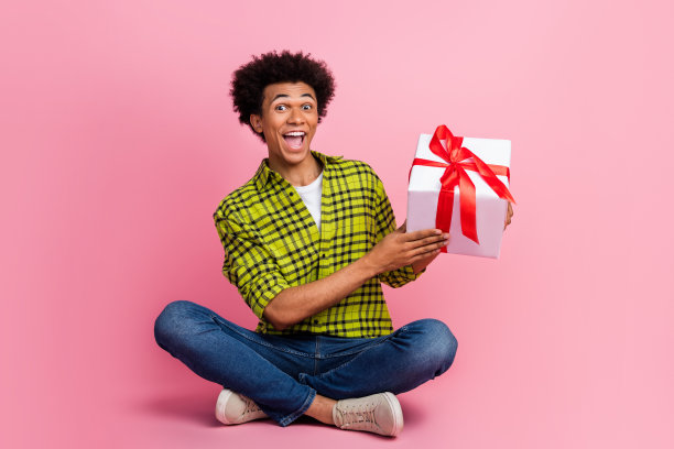 漂亮的年轻人的全尺寸照片持有礼盒穿衬衫孤立的粉红色背景图片下载