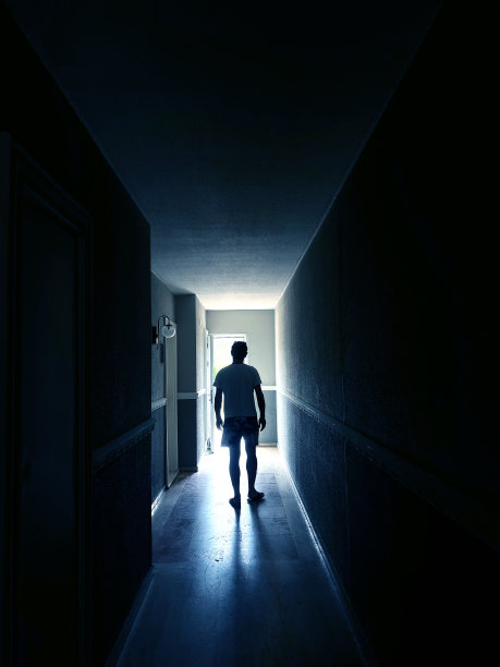 一个单身男人走在黑暗狭窄的走廊里，走进明亮的灯光图片下载