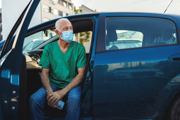 一张成年男医生戴着防护口罩坐在车里看手机的照片。一个男护士坐在车里用手机发短信。图片下载