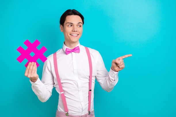 照片中的年轻男子手持标签点，看起来空无一人，穿着时髦的粉色衣服，背景是青色图片下载