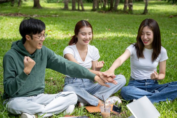 一群兴高采烈的亚洲大学生正把手放在一起的特写照片图片下载