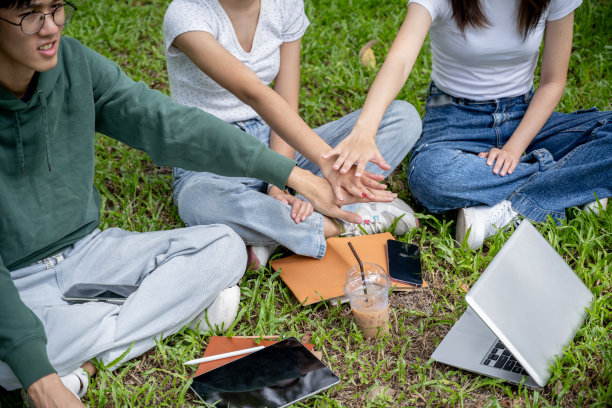 一群兴高采烈的亚洲大学生正把手放在一起的特写照片图片下载