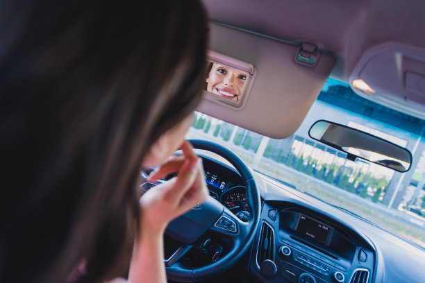 年轻欢快的漂亮女孩牙齿微笑看镜子化妆品骑汽车户外后视镜照片图片下载