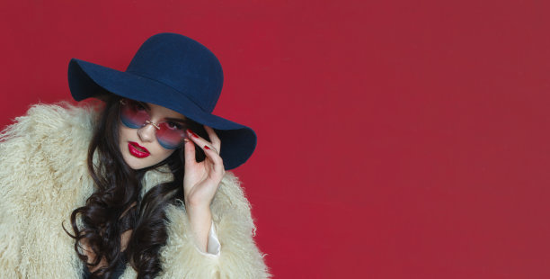 时尚模特女人的特写照片，深色波浪发型，红唇化妆，戴着时尚的帽子，美丽的工作室肖像图片下载
