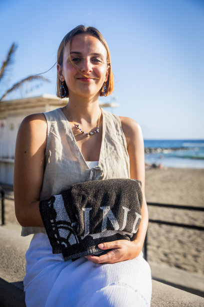 一个女人坐在沙滩边的窗台上，手里拿着毛巾，垂直照片图片下载