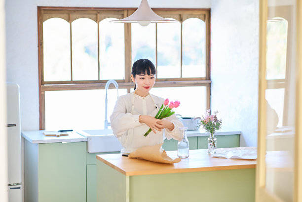 年轻女子欣赏花瓶里的花图片下载