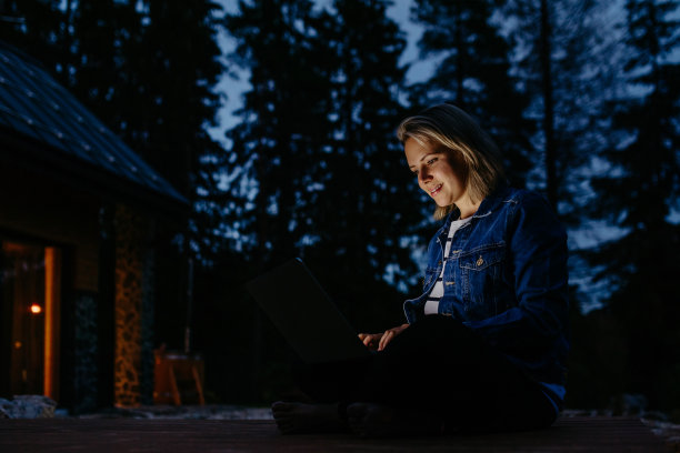 女性，自由职业者，在笔记本电脑上工作，晚上坐在户外，远程办公的概念，在假期工作。图片下载