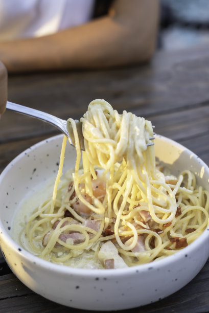 快乐的女人在餐厅吃意大利面。图片下载