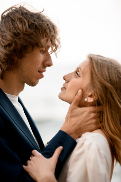 在大海和天空的背景下，新婚夫妇凝视着彼此的眼睛图片下载