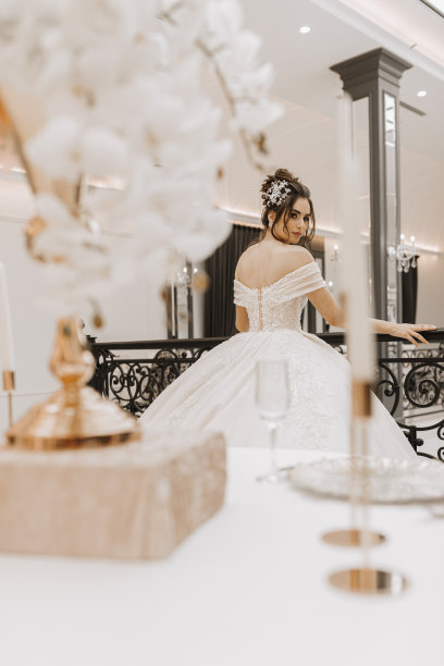 年轻的女孩，美丽的头发和化妆在豪华的婚纱与长火车附近的黑色金属栏杆。水平的照片。图片下载