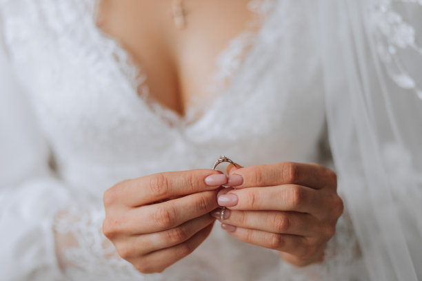 婚礼配件。新娘手里拿着一枚金戒指和一颗钻石，裁剪过的照片。美丽的手。开放破产图片下载
