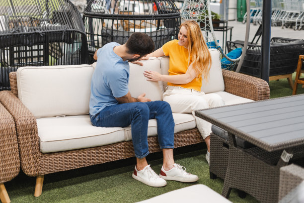 快乐的男人和女人检查沙发上的枕头，为花园露台在商店图片下载