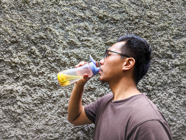 一名东南亚男子喝着注入水柠檬和草柠檬，装在瓶子里，放在户外图片下载