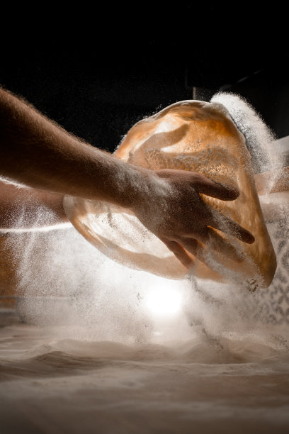 在昏暗的灯光下准备披萨前，用手揉面团图片下载